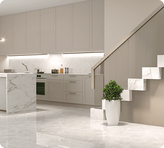 Modern kitchen with beige cabinets, a marble island, and stairs with white marble steps. A potted plant is placed near the stairs on a glossy floor.
